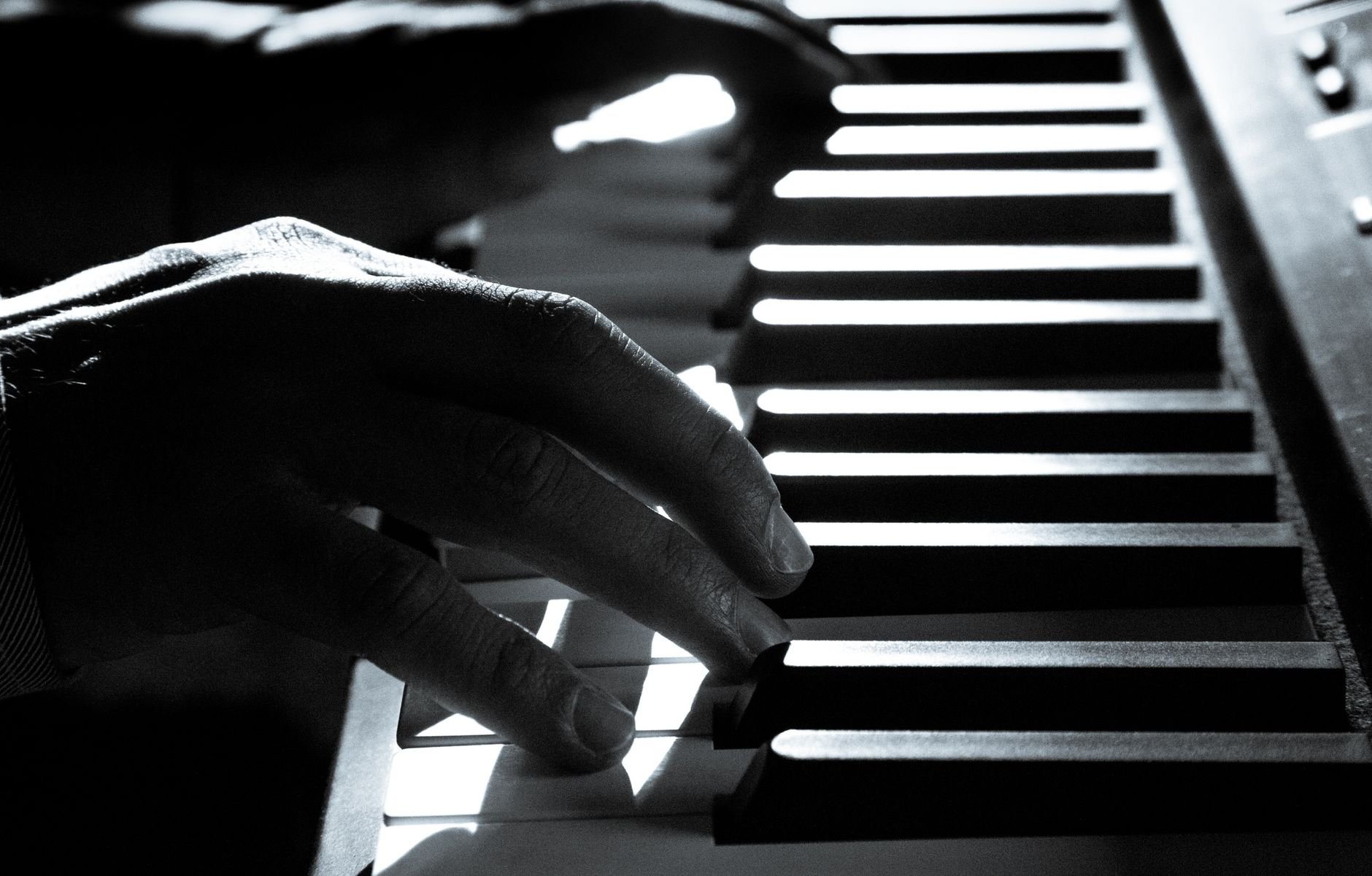 Artistic black and white close-up of a pianist's hands on piano keys, highlighting music's emotion